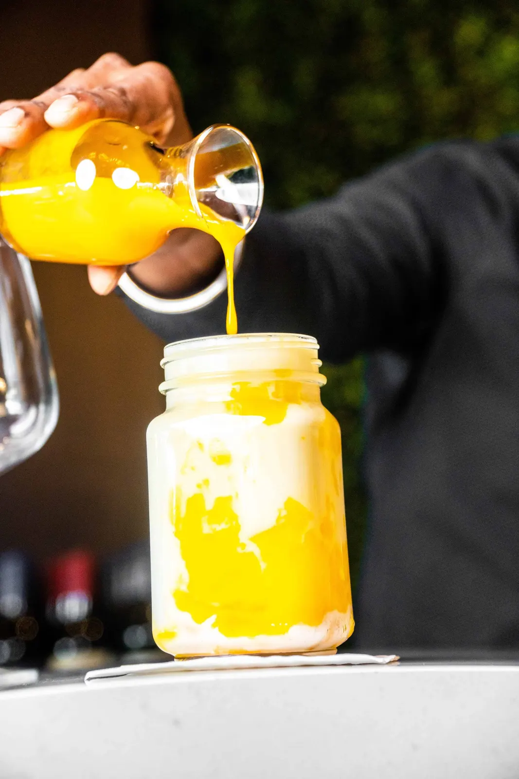 Yellow drink being poured into a jar